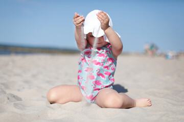 Little happy girl pouring white sand on the beach, enjoying summer, vacation