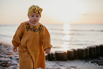 Little pensive girl on sunset beach
