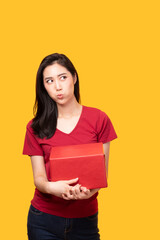 Obraz premium Delivery young female in red uniform on yellow background. Female in red doing delivery courier working. Beautiful delivery woman carrying cardboard box. Attractive delivery woman.