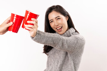 Happy Asian Woman holding cold glass of beer. Young female celebrating hold red plastic cup of cola or soda isolated on white background. Beautiful smiling woman holding beer glass while standing.