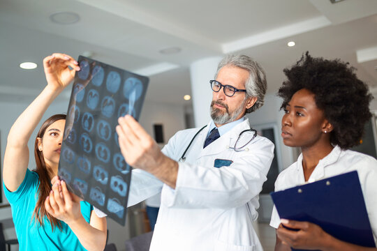 Closeup portrait of intellectual doctors healthcare personnel with white labcoat, looking at lungs x-ray radiographic image, ct scan, mri, isolated hospital clinic background. Radiology department