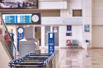 Airport luggage trolleys, flight schedules and wall clocks with copy space. Selective focus. High quality photo