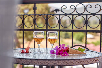 View at the balcony. Glasess of wines with pink flowers of bougainvillea on glass table. Refreshment concept. Summer bright surreal flowers and homemade drinks. Copy space. High quality photo 