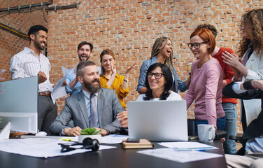 Group of excited entrepreneurs working on project indoors in office, celebrating successful...