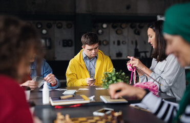 Group of people playing cards and board games in community center, inclusivity of disabled person.
