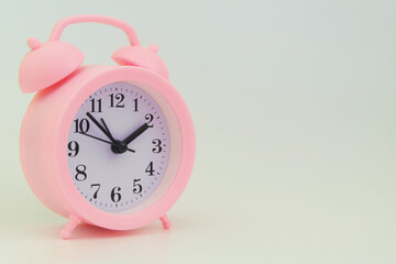 Pink alarm clock on gray background, large space for text.