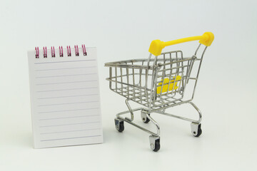 Shopping cart and blank notepad page for text, buy and sale concept