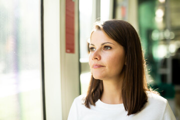 Portrait of positive girl passenger enjoying trip at public transport in modern tram