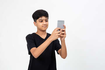 Fototapeta premium Young Indian boy taking selfies on his mobile phone. Cute teenager using his cell phone.