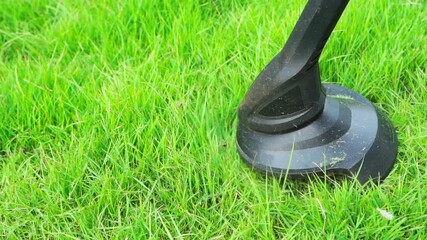slow-motion of worker using a string lawn trimmer mower cutting grass at home