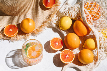 Summer fashion flat lay on white background. Holiday party, vacation, travel, tropical concept. Straw hat, refreshing drinks and citrus fruits. Palm shadow and sunlight, sun. Top view.