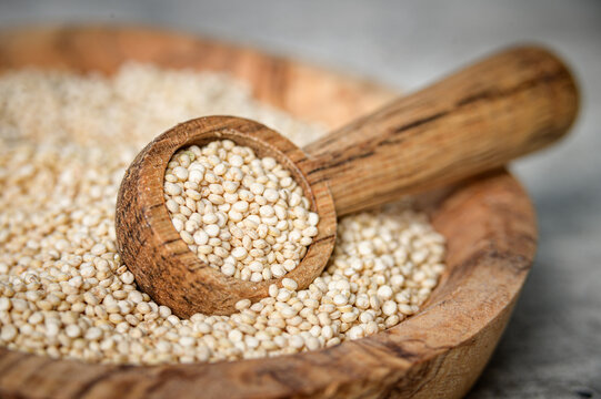 Raw white quinoa seeds on wooden spoon