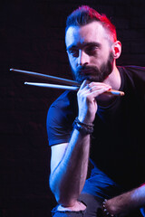 bearded brutal man with drum sticks in the image of a rock star drummer