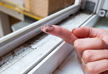 A dirty finger with dirt showing the need for cleaning the house, washing PVC window frames....