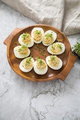 Kalte gefüllte russische Eier mit Frischkäse, Kresse und Kräuter farciert auf Holz Eierteller,...