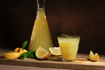 Limoncello Italian alcohol lemon liqueur and fresh lemons on dark background.