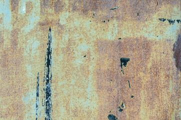 Light green metal wall with rust showing through. Chaotic black stains and streaks of paint on the...