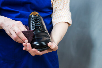 Male Shoes Cleaner with Brush For Black Leather Polished Derby Shoes Cleaning. Working in Workshop.