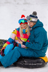 Happy Caucasian Couple Having Tube Activities In Winter Time And Posing Together For Taking Selfie In Mountains