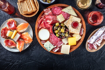 Charcuterie and cheese platter, overhead flat lay shot on a black background with a place for text. Italian antipasti or Spanish tapas, shot from above with wine and olives Mediterranean delicatessen