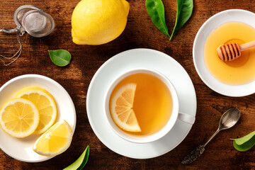 Organic tea with lemons and honey, shot from the top on a dark rustic wooden background. Natural remedy for cold