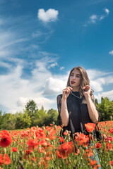 Young woman walking on red poppy field, summer time