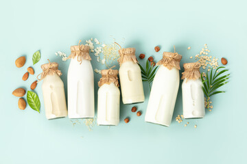 Non dairy plant based milk in bottles and ingredients on turquoise background. Alternative lactose...