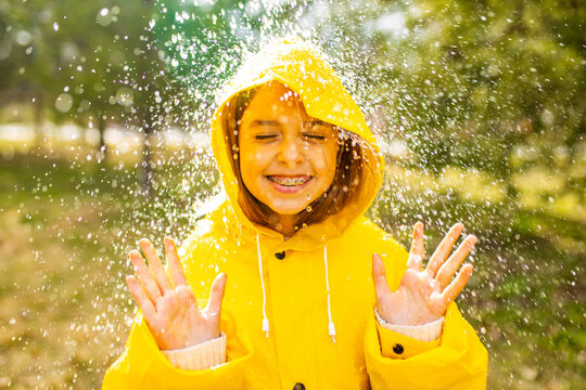 smiling teenage girl wearing raincoat outdoors in rainy day