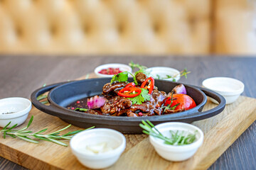 Roast meat with baked tomatoes and onions with sweet sauce, beautifully served in cast-iron dishes. Restaurant menu