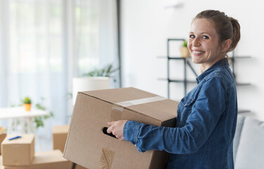 Happy woman carrying boxes in her new home