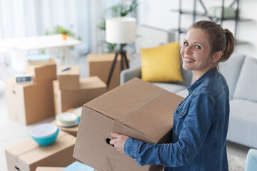 Happy woman carrying boxes in her new home