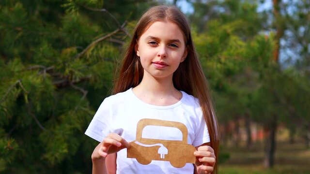 Little girl with creative craft hobby paper car environment, eco friendly, save energy in park at summer day