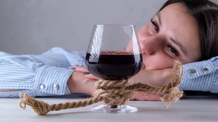 sad female looking wine glass tied with jute rope. The concept of alcohol addiction. The problem of alcoholism treatment