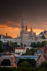 Fototapeta na wymiar Budapest, Hungary - St Matthias Church and Fisherman's Bastion (Halaszbastya) with Statue of Gyula Andrassy in foreground and beautiful golden sunset and dramatic sky on a summer afternoon
