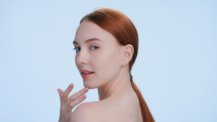 Close-up beauty portrait of young ginger woman demonstrates her perfect skin sliding fingers from...