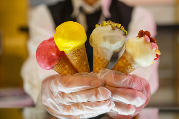 Commessa di una gelateria mentre regge 4 piccolini coni gelato preconfezionati