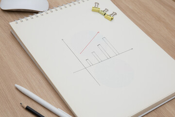 Drawing a graph of growth in a notebook on your desk at home.Wooden work table
