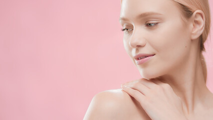 Fit attractive European blonde skin care woman touches her naked shoulder and turns her head to the...