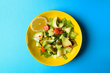 Vegetable salad made of fresh cucumbers, cherry tomatoes, avocado, lettuce salad and lemon.