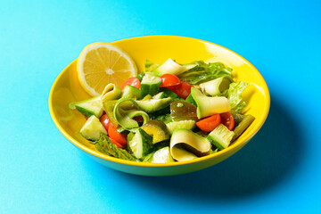 Vegetable salad made of fresh cucumbers, cherry tomatoes, avocado, lettuce salad and lemon.