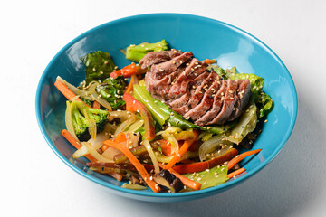 Fresh summer salad with stripes of fried beef and avocado slices, radish, sprouts, broccoli and ginger