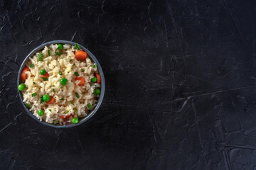 White rice with veggies, shot from the top on a black background with copy space