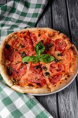Fresh italian pizza with salami and black olives. Traditional Italian pizza recipe, Italian cuisine.