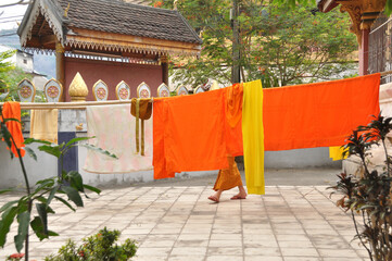 Monk hanging orange clothes in the temple