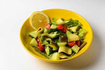 Vegetable salad made of fresh cucumbers, cherry tomatoes, avocado, lettuce salad and lemon.