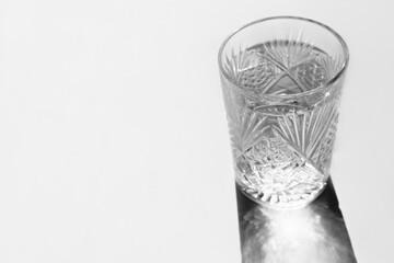 still clear water in a crystal glass. shadows and reflects. copy space. fresh water concept