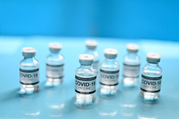 Coronavirus COVID-19 Vaccine Glass Bottle on blue surface with blue background at Thailand. Concept viruses spread throughout the world. Selective Focus.