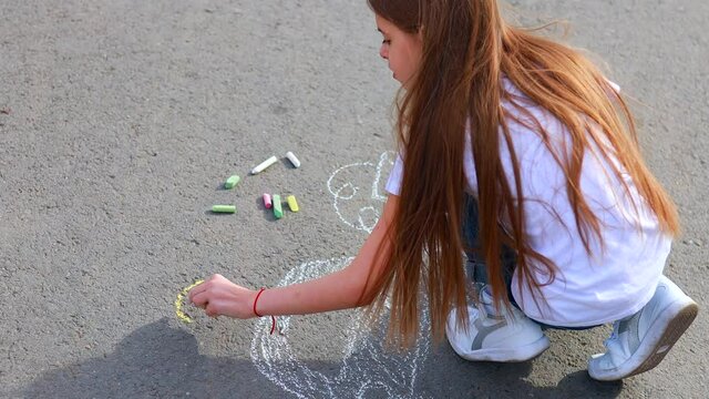 Little girl with creative craft hobby drawing electro on the asphalt with chalk car environment, eco friendly, save energy in park at summer day