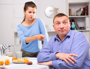 Wife threatens the finger of her husband at kitchen. High quality photo