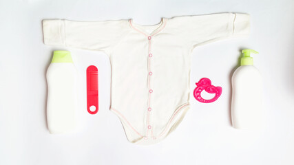 Baby bath set. Baby acessories and clothers. Soap, hairbrush, Shampoo, bodusuit on white background top view